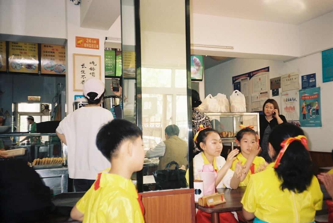 Kinder in leuchtend gelben, einheitlichen Outfits sitzen an Tischen in einem asiatischen Restaurant.